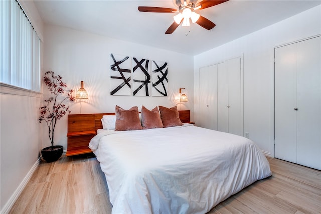 bedroom featuring multiple closets, ceiling fan, and light hardwood / wood-style floors