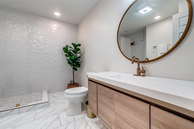 bathroom featuring vanity, toilet, and tiled shower