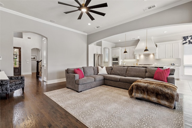 living room with hardwood / wood-style floors, crown molding, and ceiling fan