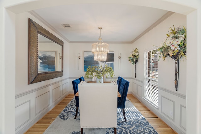 dining area featuring a chandelier, light hardwood / wood-style floors, and crown molding