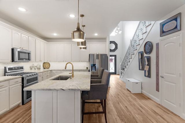 kitchen with decorative light fixtures, light stone countertops, sink, and appliances with stainless steel finishes