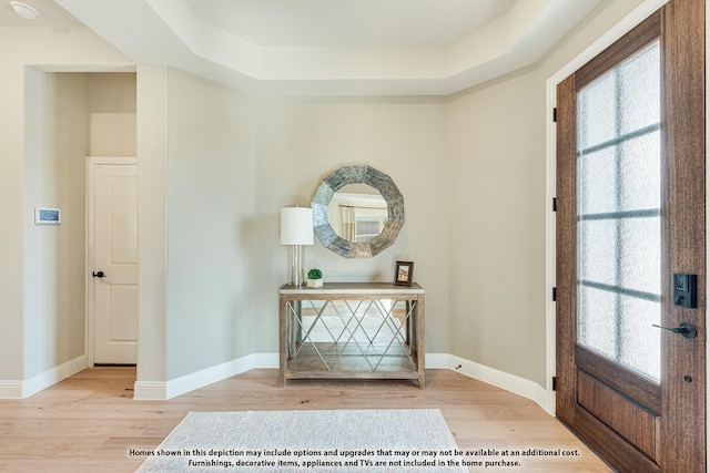 entryway with a tray ceiling and light hardwood / wood-style flooring