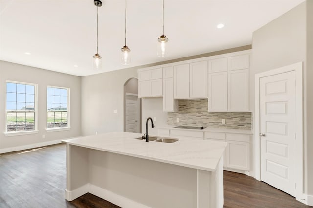 kitchen with sink, white cabinetry, light stone countertops, an island with sink, and decorative light fixtures