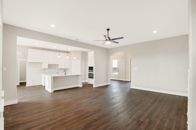 unfurnished living room with sink, dark hardwood / wood-style floors, and ceiling fan