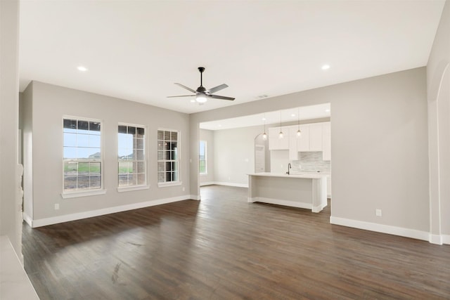 unfurnished living room with a wealth of natural light, ceiling fan, and dark hardwood / wood-style floors