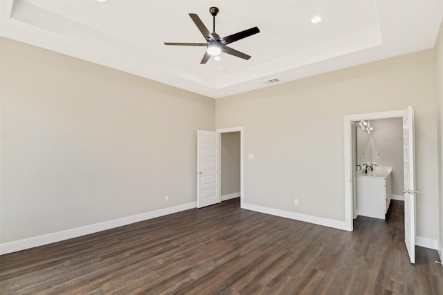 unfurnished bedroom featuring ceiling fan, dark hardwood / wood-style floors, and a raised ceiling