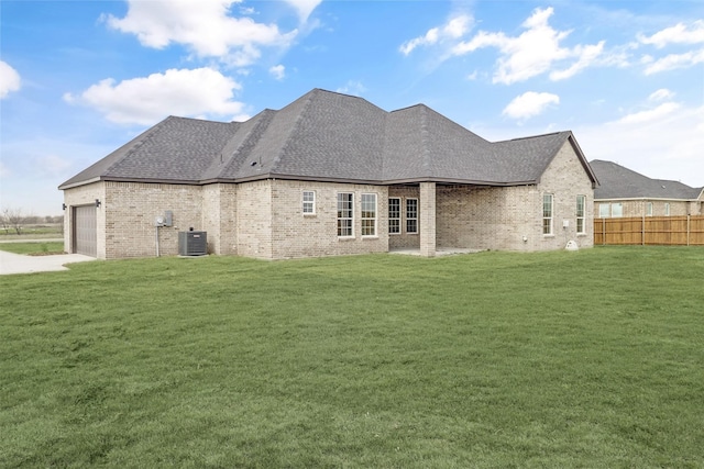 back of house with a yard, a garage, and central air condition unit