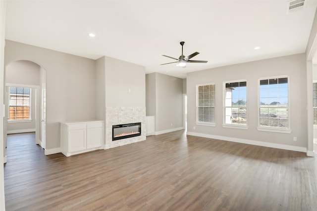 unfurnished living room featuring hardwood / wood-style flooring, a stone fireplace, and ceiling fan