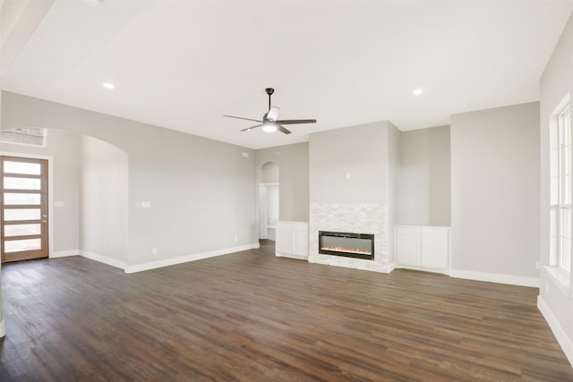 unfurnished living room featuring a fireplace, dark hardwood / wood-style flooring, and ceiling fan