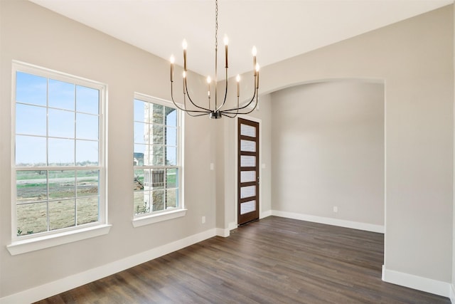 unfurnished dining area with plenty of natural light, an inviting chandelier, and dark hardwood / wood-style flooring