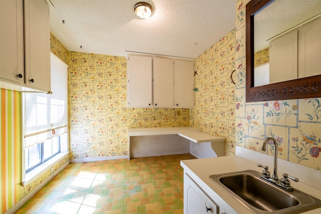 kitchen featuring white cabinets, sink, and a textured ceiling