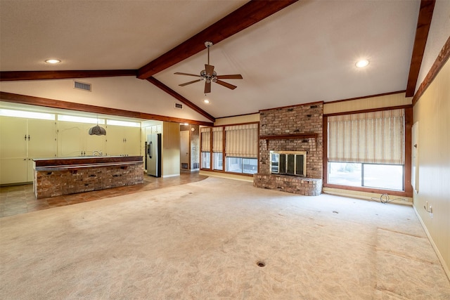 unfurnished living room with ceiling fan, lofted ceiling with beams, light colored carpet, and a fireplace