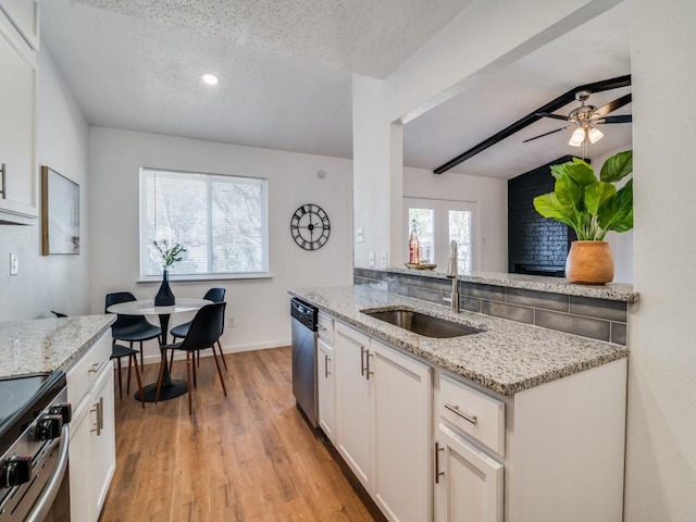 kitchen with white cabinets, a textured ceiling, light stone countertops, and sink