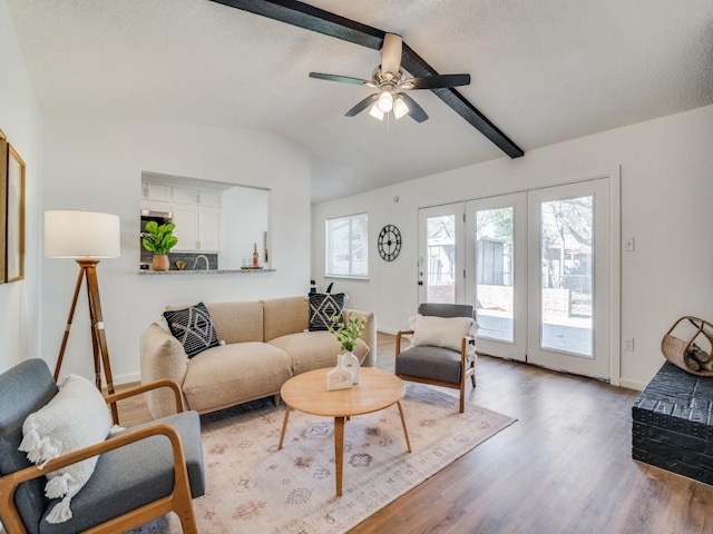 living room with french doors, hardwood / wood-style flooring, vaulted ceiling with beams, ceiling fan, and a textured ceiling