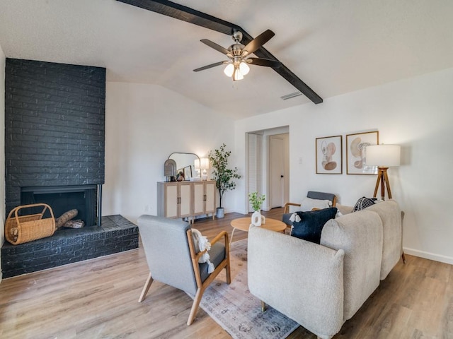 living room featuring vaulted ceiling with beams, hardwood / wood-style flooring, a brick fireplace, and ceiling fan