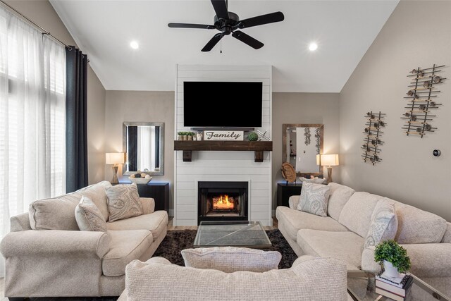 living room featuring a fireplace, ceiling fan, and lofted ceiling