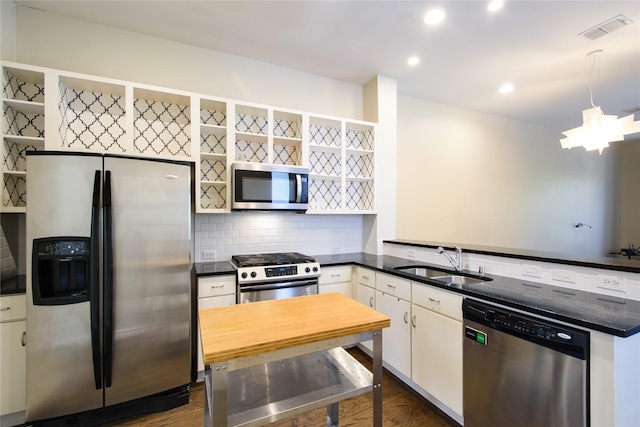 kitchen with tasteful backsplash, white cabinetry, sink, stainless steel appliances, and dark wood-type flooring