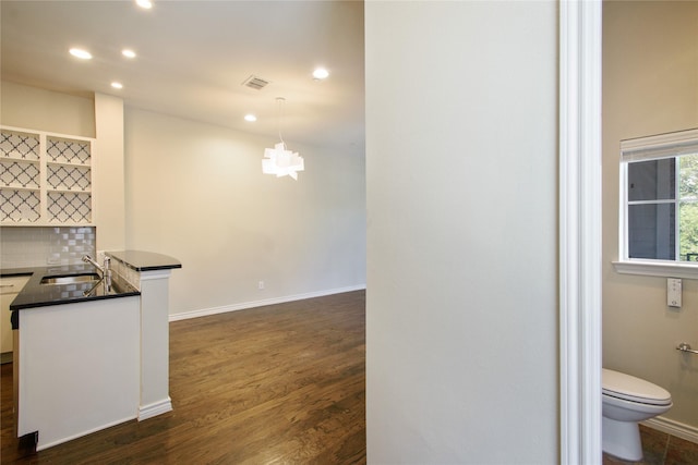 kitchen featuring pendant lighting, sink, white cabinets, dark hardwood / wood-style flooring, and decorative backsplash