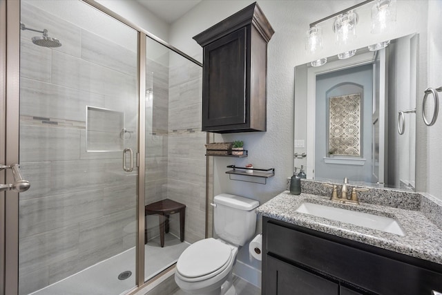 bathroom featuring vanity, toilet, and a shower with door