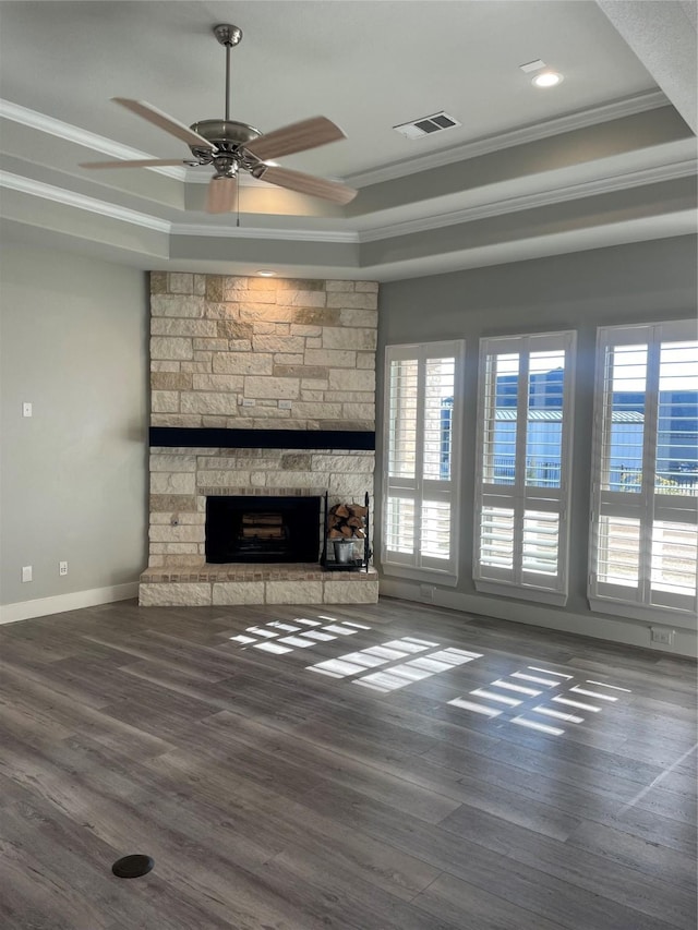 unfurnished living room with dark hardwood / wood-style flooring, a raised ceiling, ceiling fan, crown molding, and a stone fireplace