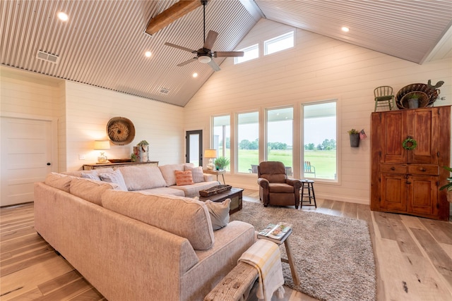 living room featuring light hardwood / wood-style floors, high vaulted ceiling, ceiling fan, and wooden walls