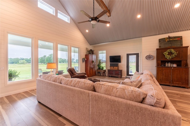 living room with a wealth of natural light, light hardwood / wood-style floors, high vaulted ceiling, and ceiling fan