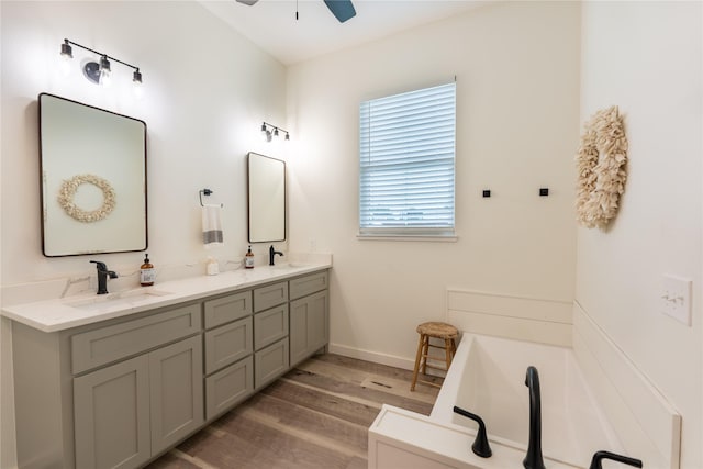 bathroom featuring hardwood / wood-style floors, vanity, ceiling fan, and a bathing tub