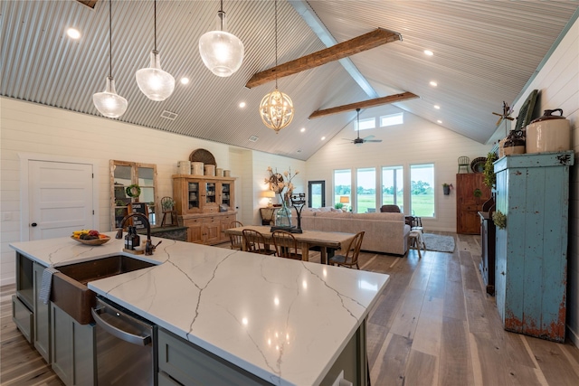 kitchen featuring a kitchen island with sink, ceiling fan, pendant lighting, and light stone counters