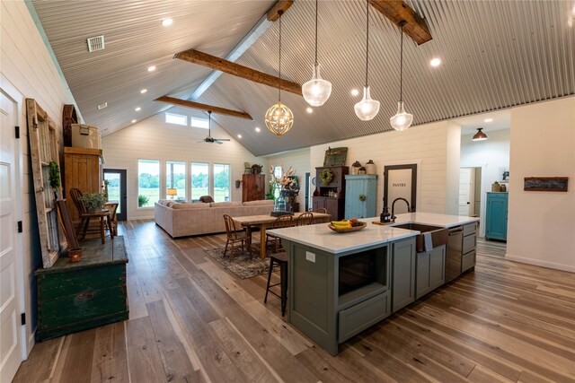 kitchen with high vaulted ceiling, a center island with sink, hanging light fixtures, ceiling fan, and dark hardwood / wood-style flooring