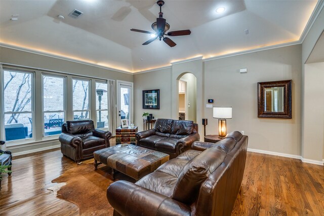 living room featuring hardwood / wood-style floors, lofted ceiling, a raised ceiling, crown molding, and ceiling fan