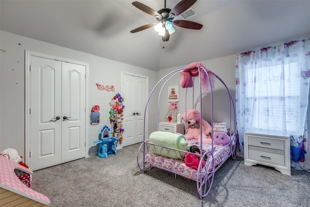 bedroom featuring ceiling fan, lofted ceiling, carpet, and two closets