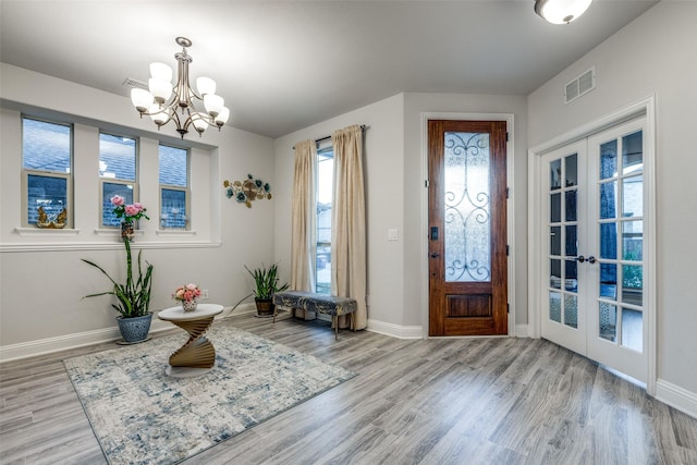 foyer with an inviting chandelier, french doors, and light wood-type flooring