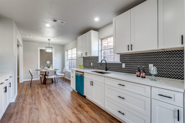 kitchen with white cabinetry, sink, stainless steel dishwasher, pendant lighting, and light hardwood / wood-style floors