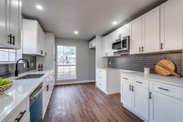 kitchen with appliances with stainless steel finishes, backsplash, sink, dark hardwood / wood-style floors, and white cabinetry