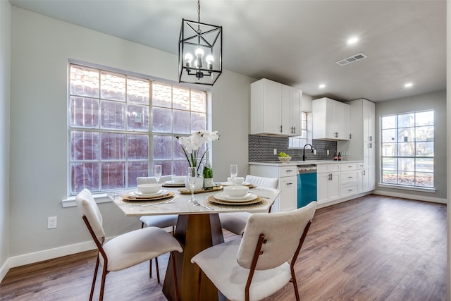 dining space with sink, light hardwood / wood-style flooring, and an inviting chandelier