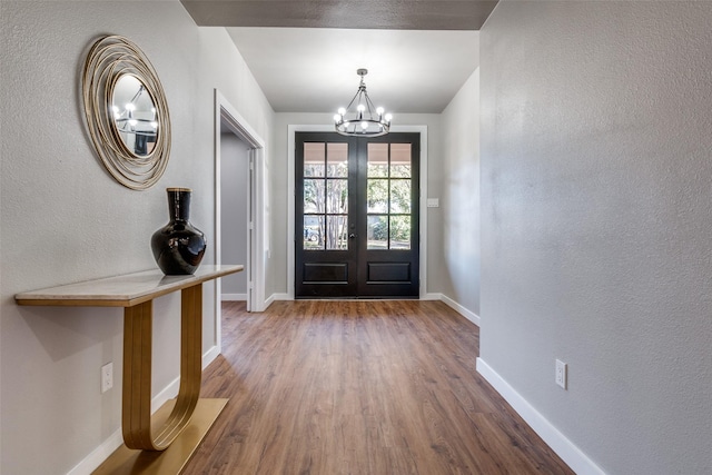 entrance foyer with french doors, a chandelier, and hardwood / wood-style flooring