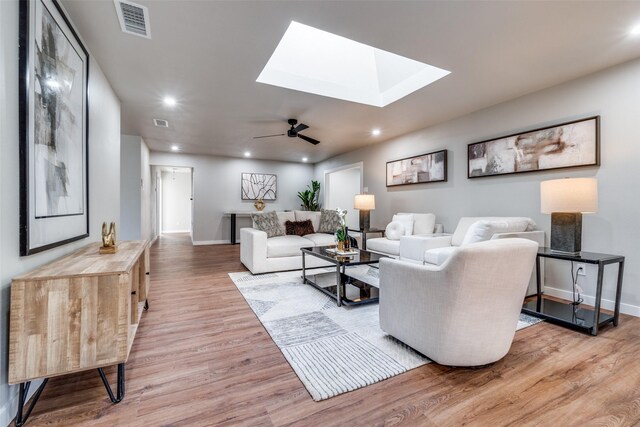 living room with a skylight, ceiling fan, and hardwood / wood-style flooring