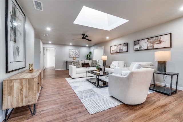 living room with hardwood / wood-style flooring, a skylight, and ceiling fan