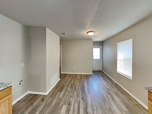 spare room with a textured ceiling and light hardwood / wood-style floors