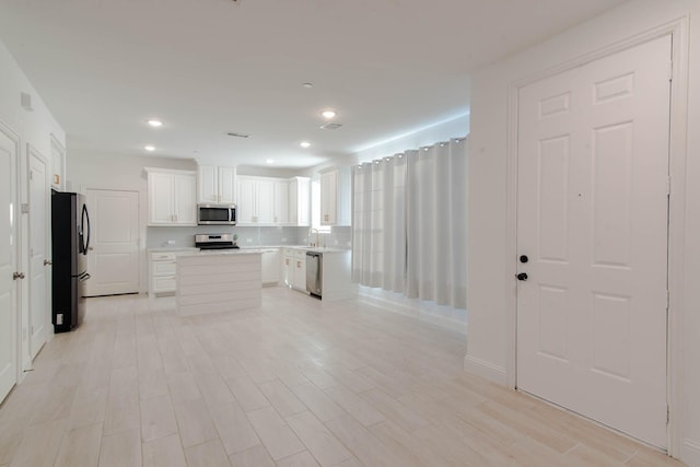 kitchen featuring stainless steel appliances, a kitchen island, white cabinetry, and sink