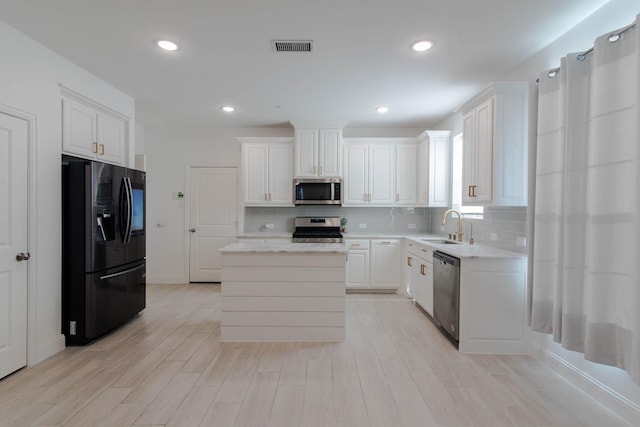 kitchen with a center island, backsplash, sink, white cabinetry, and stainless steel appliances