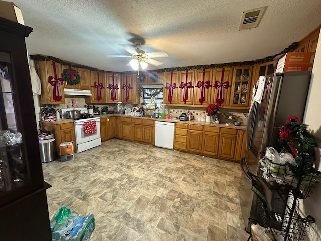 kitchen featuring a textured ceiling, ceiling fan, tasteful backsplash, and white appliances