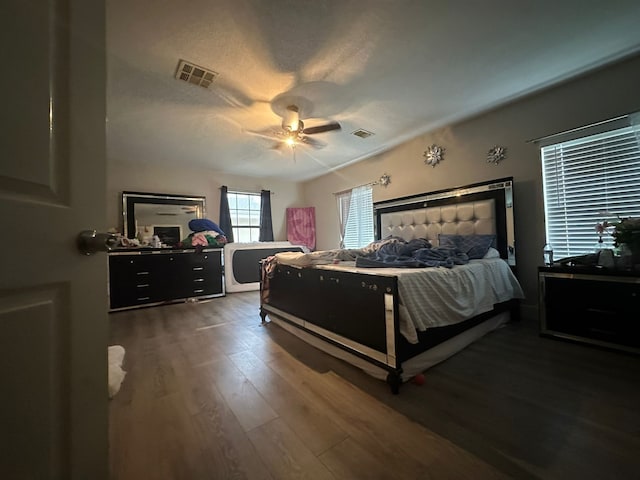 bedroom featuring ceiling fan, dark wood-type flooring, and a textured ceiling