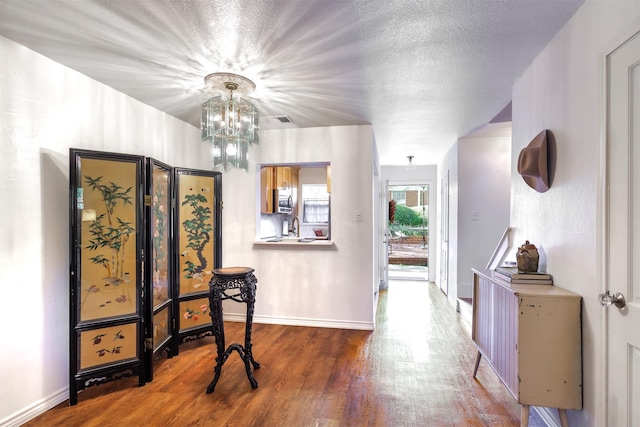 entryway featuring hardwood / wood-style floors, a chandelier, sink, and a textured ceiling