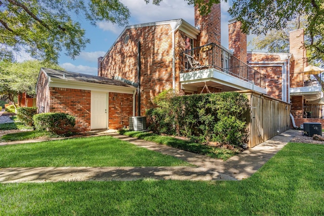 back of house featuring central AC unit, a lawn, and a balcony