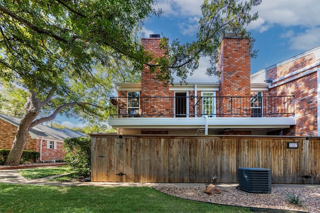 rear view of house featuring a balcony and a yard