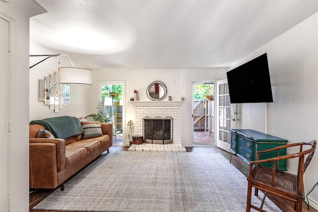 living room with a brick fireplace and dark wood-type flooring