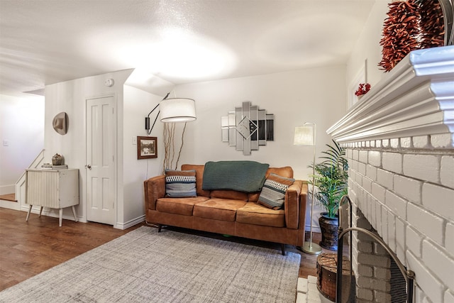 living room with wood-type flooring and a brick fireplace