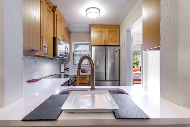 kitchen featuring stainless steel appliances, tasteful backsplash, sink, and kitchen peninsula