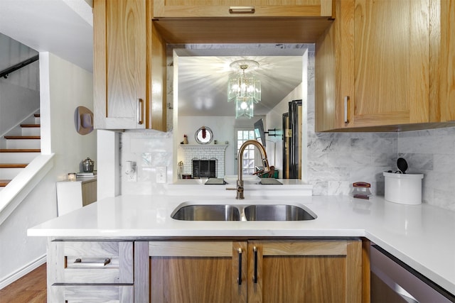 kitchen featuring pendant lighting, dishwasher, sink, decorative backsplash, and hardwood / wood-style flooring